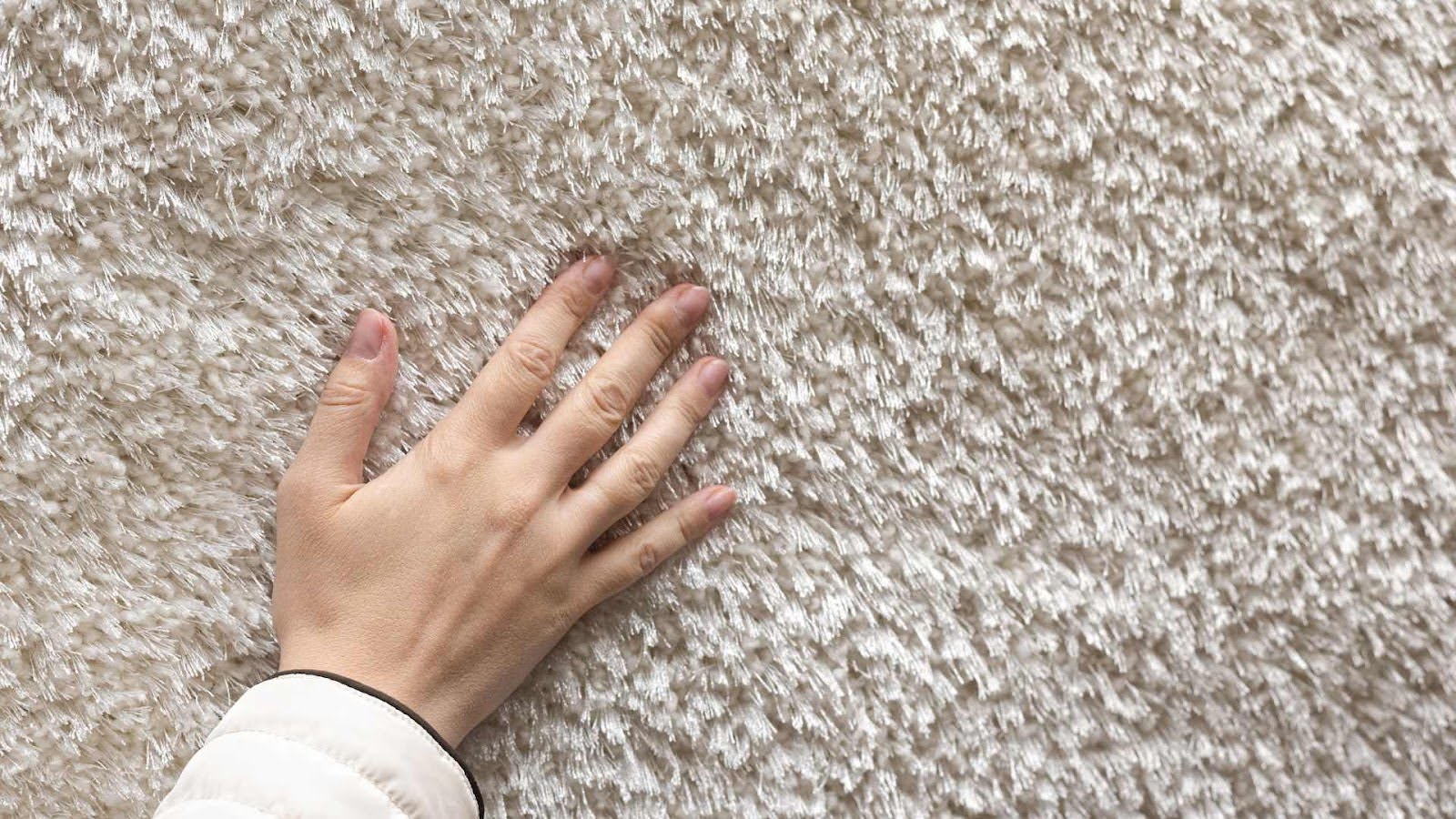 Hand touching and testing the texture of a soft carpet surface 